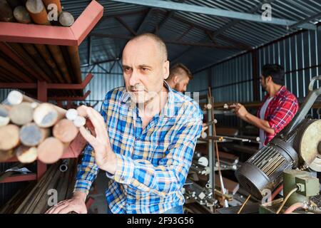 Metal worker come addetto al magazzino durante il controllo dell'inventario in magazzino dei materiali della bottega del fabbro Foto Stock