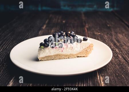 Cheesecake fresco con mirtilli selvatici su sfondo rustico. Messa a fuoco selettiva. Profondità di campo poco profonda. Foto Stock