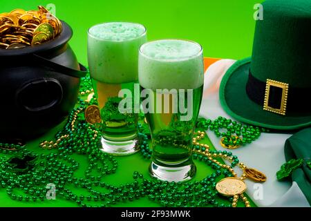 La fortuna della meme irlandese e Happy St Patricks giorno concept tema con due bicchieri di birra tinta, cappello leprechaun, collana di perle e pentola di monete d'oro Foto Stock