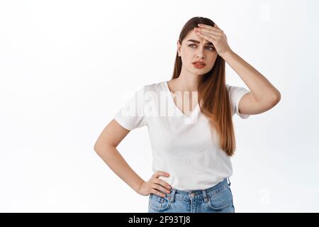 Giovane donna turbata e afflitta che tocca fronte, guardando da parte penosa, hanno problemi, situazione difficile, in piedi disturbati e stressati contro Foto Stock