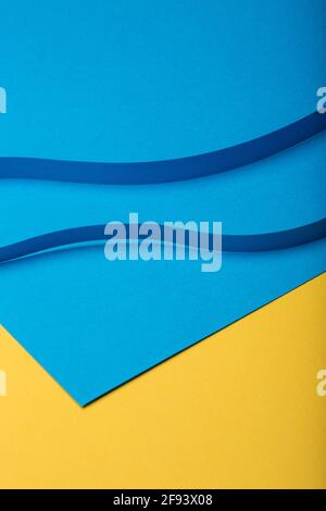 Astratto sfondo minimo della carta. Due strisce di carta blu con taglio curvo su sfondo di carta blu e giallo. Foto Stock