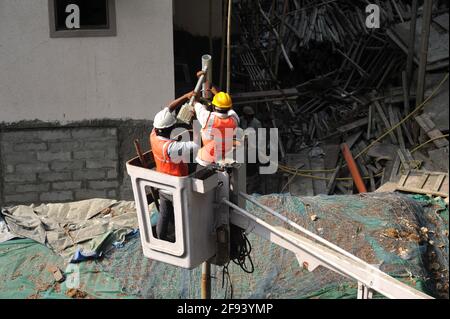 Lavoratori municipali con casco e dispositivi di protezione di sicurezza installano nuovi Diodo luci lavoro nel braccio di riparazione benna di sollevamento del lampioni stradali Foto Stock