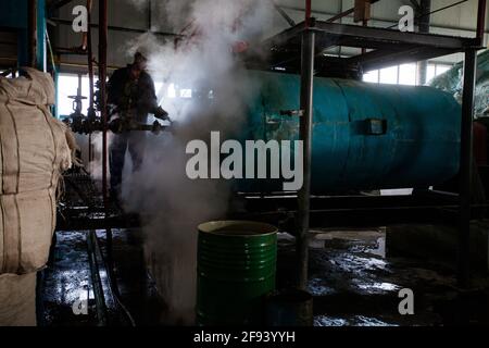 Shymkent/Kazakhstan - Aprile 27 2012: Officina di fabbrica e attrezzature per il riciclaggio del vetro.lavoratore in nuvola di vapore. Produzione di vetro. Società Ferrum Vtor. Foto Stock