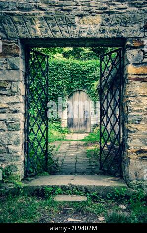 Due misteriose porte nel vecchio muro di pietra del castello, coperto di edera Foto Stock