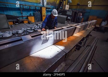 Lavoratore e grande parte metallica. Officina meccanica. Preparazione per la saldatura. Foto Stock