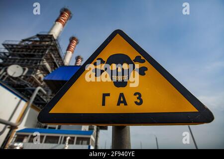 Moderna centrale a gas. Simbolo di avvertimento giallo triangolare pericoloso. Titolo sul cartello: Gas. Pile fumanti su cielo blu. Città di Uralsk, Kazakistan. Foto Stock