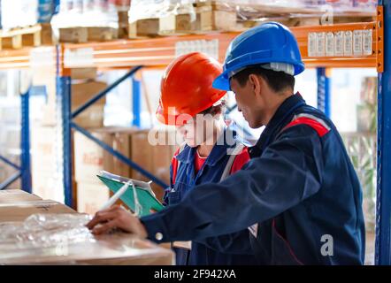 Due operatori asiatici nel centro di distribuzione e nel magazzino. Aktobe, Kazakistan. Foto Stock