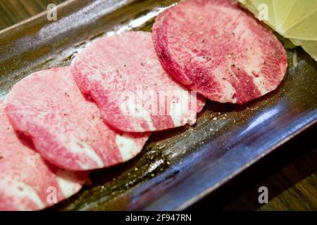 Atsui Tan, lingua Ox tagliata a fette servita su un vassoio nero con limone. Foto Stock