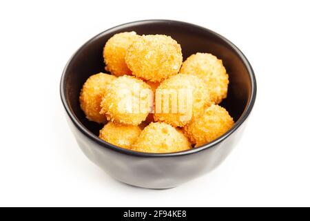 Palline di formaggio in un recipiente nero isolato su bianco dall'alto. Palle di formaggio dorato soffiato come classico spuntino per bambini su sfondo di legno Foto Stock