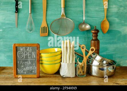 cartello di riapertura del ristorante con aspargus fresco, utensili da cucina e messaggio sulla lavagna, riavviare il cibo e bevande dopo il blocco corona Foto Stock