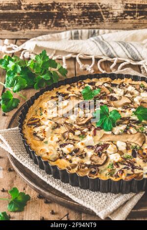 Quiche di funghi vegetariani con prezzemolo su tavola di legno, verticale Foto Stock