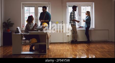 Team di giovani ingegneri moderni che lavorano insieme in ufficio. Foto Stock