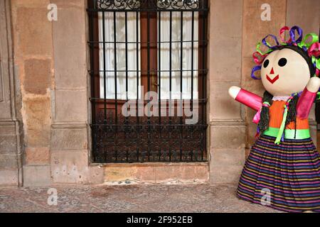 Vetrina artigianale con griglie in ferro su un muro di pietra e una colorata 'Maria', la tradizionale bambola di rag messicana fatta a mano a Santiago de Querétaro Messico. Foto Stock