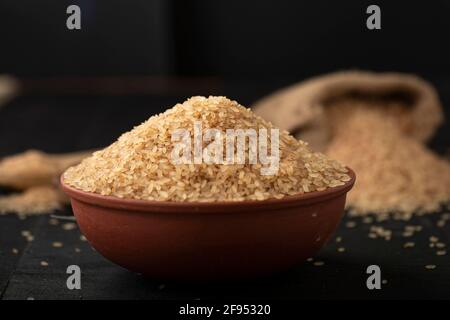 Riso Kerala Matta  riso parboiled o palakadan matta o riso rosso arrangiato in terracotta su tessuto grigio con fondo cucina. Foto Stock