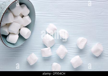 Marshmallow bianco in una tazza su uno sfondo di legno chiaro. Foto Stock