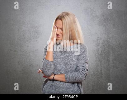 Donne con un volto triste. Su un fondo grigio concreto., donne con un volto triste. Su uno sfondo grigio di cemento. Foto Stock