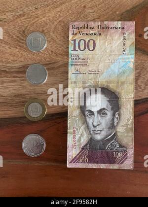 Valuta dal Venezuela. Bolivares conosciuto come banconote, banconote e monete su uno sfondo di legno Foto Stock