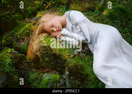 Bella giovane donna in un vestito bianco al centro di una foresta Foto Stock