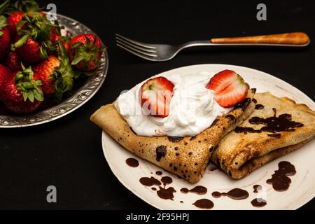 pancake con cioccolato, fragole e panna montata Foto Stock
