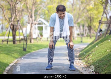 ritratto di sano sportivo maschio maturo in felpa con cappuccio e scarpe da running che si esercitano all'aperto, pratica affondo laterali. Uomo anziano sopportato in sportswear caldo Foto Stock