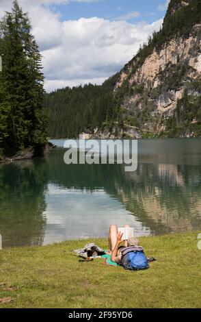 Uomo sdraiato sulle rive del lago Braies Foto Stock