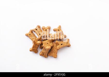 Pila di biscotti marroni a forma di osso per cani su sfondo bianco Foto Stock