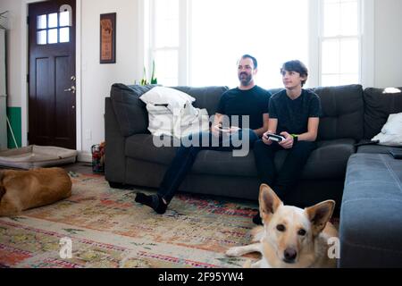 Padre e figlio giocano insieme i videogiochi sul divano. Foto Stock