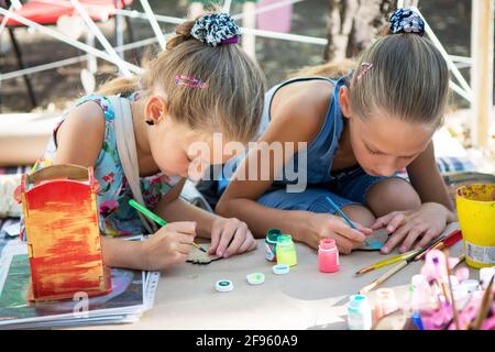 Le ragazze dipingono con vernici su sbozzi di legno. Festival dell'arte di strada Foto Stock