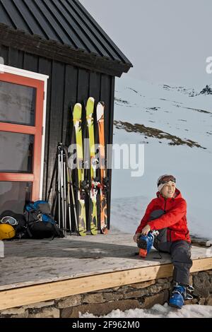 Donna che si prepara per lo sci alpinismo a casa di sci in Islanda Foto Stock