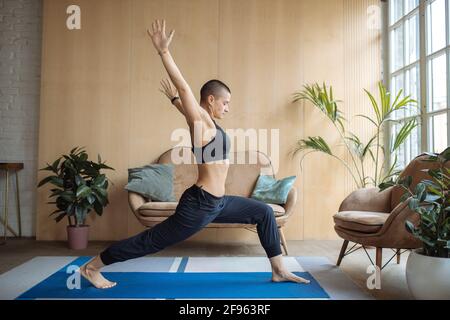 donna atletica facendo affondo stretching esercizio a casa Foto Stock