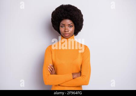 Foto di grave signora rigida attraversata mani guardare fotocamera usura turtleneck arancione isolato di colore grigio sfondo Foto Stock