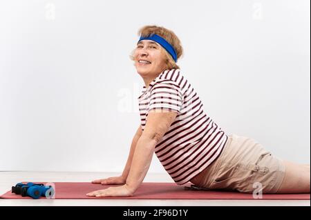 Donna anziana che fa esercizi in studio su sfondo bianco. La vecchia signora sta facendo il fitness per la salute Foto Stock