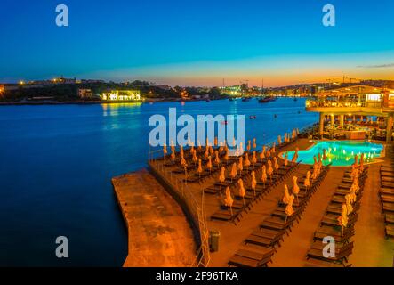 Vista notturna di un bar con piscina a Sliema, Malta Foto Stock