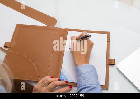Primo piano di notepad e la donna di affari che scrive Foto Stock