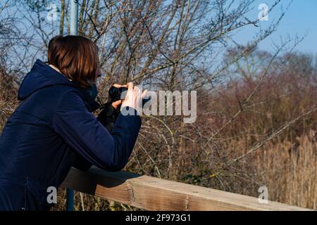 Donna con Binocolo che guarda gli uccelli nella laguna di Marano Foto Stock