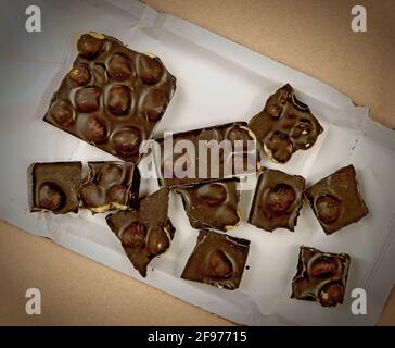 frammenti di cioccolato fondente con nocciole intere su un bianco foglio di imballaggio Foto Stock