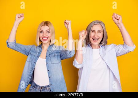 Ritratto fotografico di madre e figlia che ridono gesturing come vincitore sfondo isolato di colore giallo vivo Foto Stock