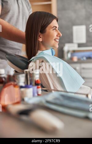 Bella donna visita clinica dentale. Felice giovane donna seduta in sedia dentale presso l'ufficio dentista Foto Stock