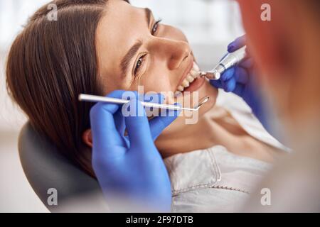 Paziente femminile alla procedura dentale, medico che utilizza strumenti dentali in moderna clinica dentale. Foto Stock