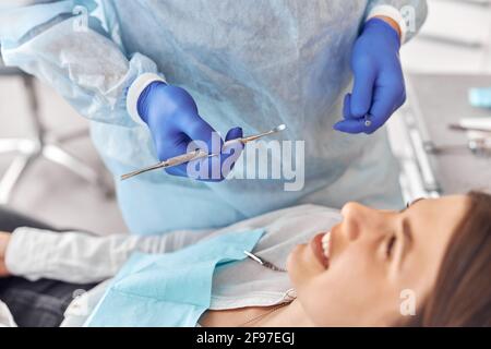 Ritratto di giovane dentista in guanti che esamina i denti di femmina cliente in ospedale Foto Stock