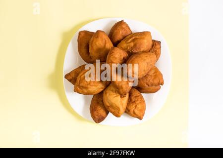 Torte ripiene fritte su un piatto bianco servite su sfondo giallo. Foto Stock