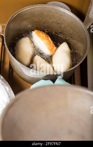 Preparare torte con ripieno a casa e friggere in olio in calderone. Foto Stock