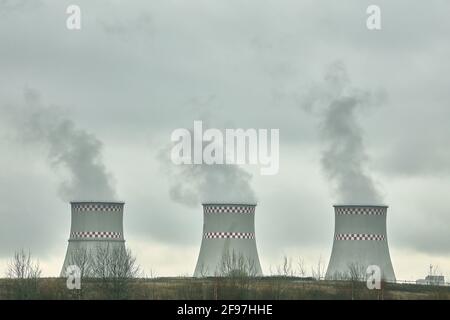 Tre camini di una centrale termica sullo sfondo di un cielo nuvoloso Foto Stock