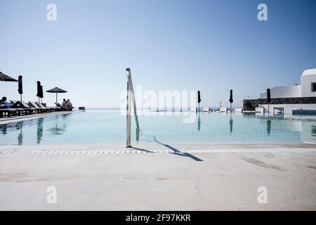 Una piscina in un resort a Oia sull'isola di Santorini con le tradizionali case bianche e cicladiche e chiese con cupole blu sulla Caldera, Mar Egeo, Grecia, Foto Stock