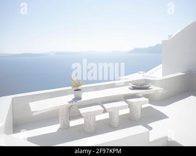 Vista panoramica di un balcone bianco con un fiore a Oia, sull'isola di Santorini, con le tradizionali case bianche delle cicladi e le chiese con cupole blu sulla Caldera, sul Mar Egeo, Grecia, Foto Stock