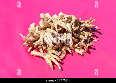 Mucchio di piedi di pollo in un mercato cinese su un sfondo rosa Foto Stock