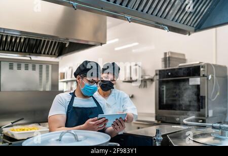 cucina guardando le ricette del menu sul tablet Foto Stock