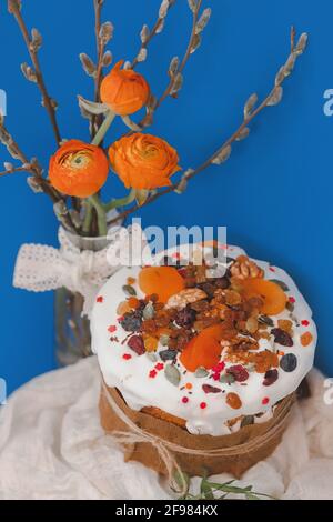 Torta di Pasqua, panettone pasquale naturale con frutta secca, noci e fiori sul tavolo festivo Foto Stock