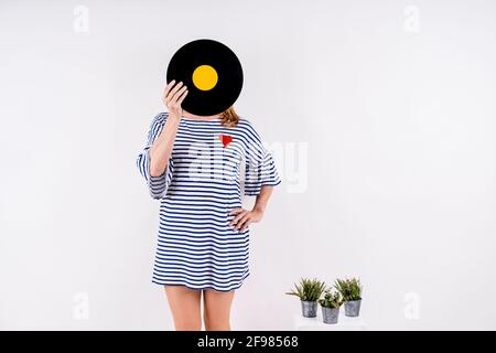 Ragazza vestita con abito a righe blu e bianco che tiene un disco in vinile o Foto Stock