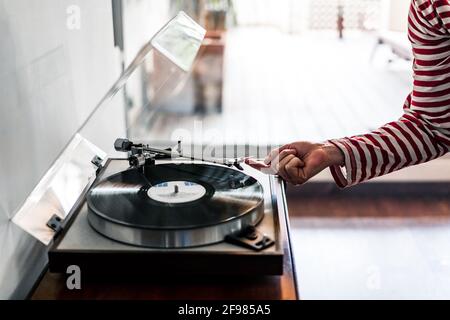 donna che mette un disco in vinile su un lettore di dischi all'interno una casa Foto Stock